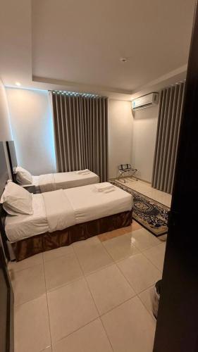 a hotel room with two beds and a bathroom at الجوهرة البيضاء للشقق المخدومة in Taif