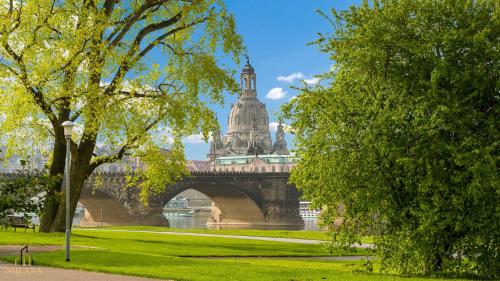 eine Brücke über einen Fluss mit einem Gebäude in der Unterkunft Royal Garden Residence in Dresden