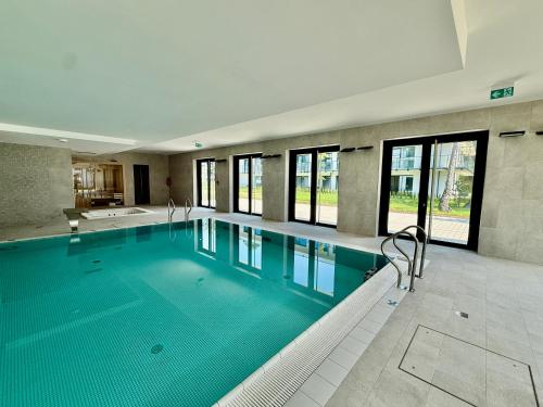 a large swimming pool with blue water in a building at Rezydencja Niechorze MORSKIE WIDOKI 313 z Basenem i SPA - 5D Apartments in Niechorze