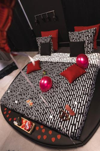 a black and white bed with red pillows on it at Love room - L'escapade du désir in Trouillas
