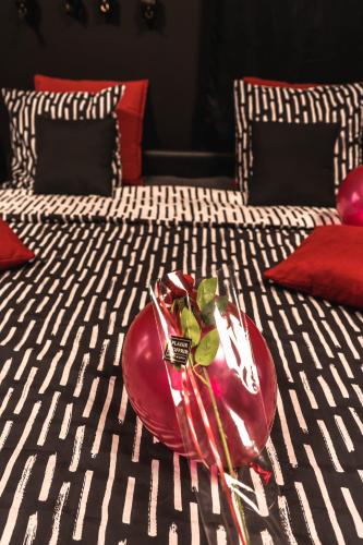 a red plate with a plant on a bed at Love room - L'escapade du désir in Trouillas