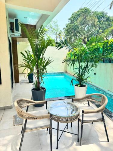 a patio with two chairs and a table and a pool at The Soul Stones Villas in Vagator
