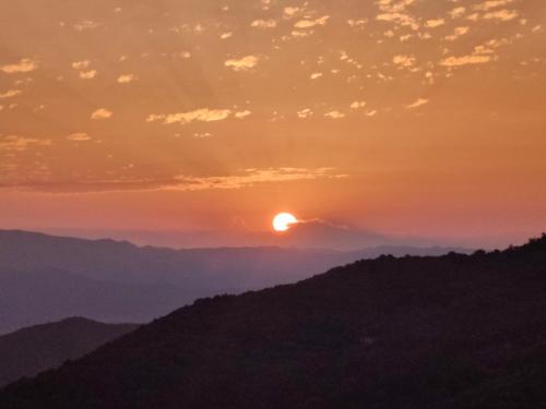 a sunset over the mountains with the sun in the sky at Locanda di Bivigliano in Bivigliano