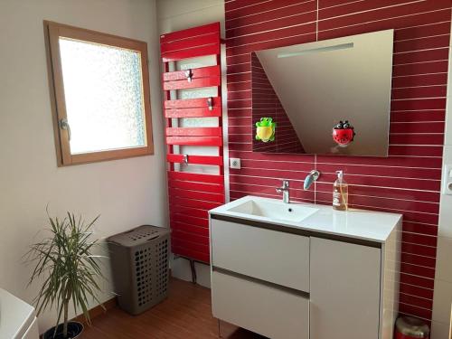 La salle de bains est pourvue d'un lavabo et d'un mur rouge. dans l'établissement Le Cocon des Volcans d'Auvergne, à La Chapelle-dʼAlagnon