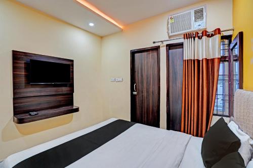 a bedroom with a bed with a television and a window at Hotel O MVD Inn Gomti Nagar in Lucknow