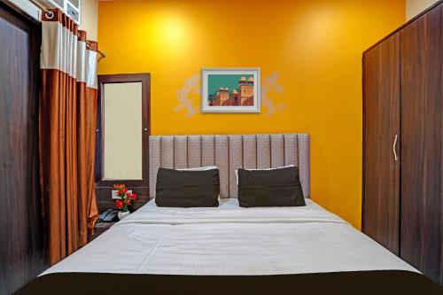 a bedroom with a large bed with yellow walls at Hotel O MVD Inn Gomti Nagar in Lucknow