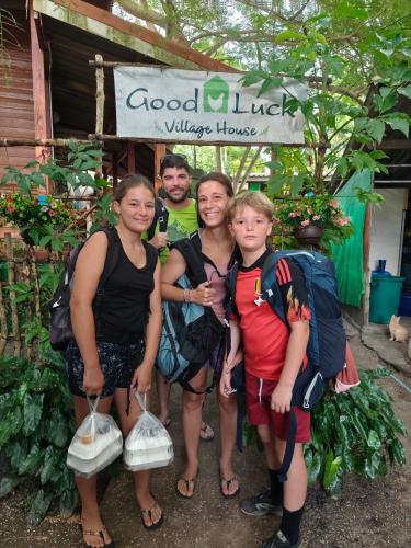 a group of people standing in front of a sign at Goodluck village house in Koh Mook