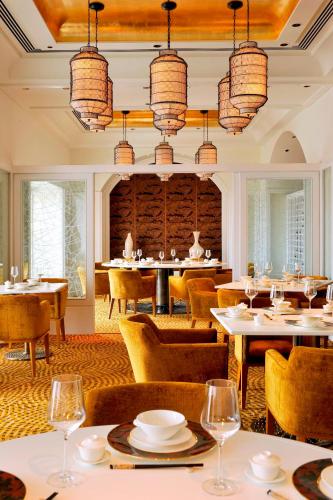 a dining room with tables and chairs and chandeliers at The Taj Mahal Tower, Mumbai in Mumbai