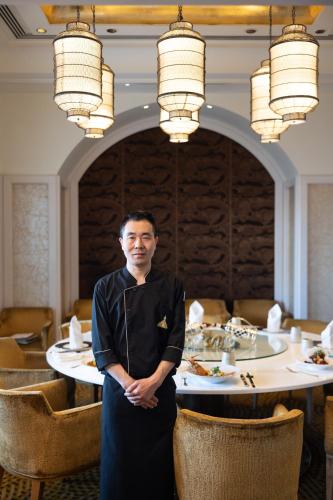 a man standing in front of a table in a restaurant at The Taj Mahal Tower, Mumbai in Mumbai