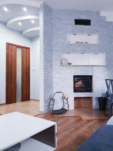 a living room with a fireplace and a white brick wall at Apartamenty Biały Kamień in Wałbrzych