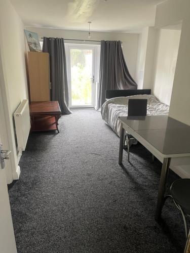 a bedroom with a bed and a desk and a window at ComfortVilla FH in Hornchurch