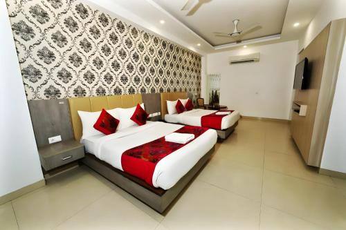 two beds in a hotel room with red pillows at Almati Hotel - Near Delhi Airport With - free Airport Pickup in New Delhi