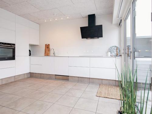 a kitchen with white cabinets and a tile floor at 8 person holiday home in Blåvand in Blåvand