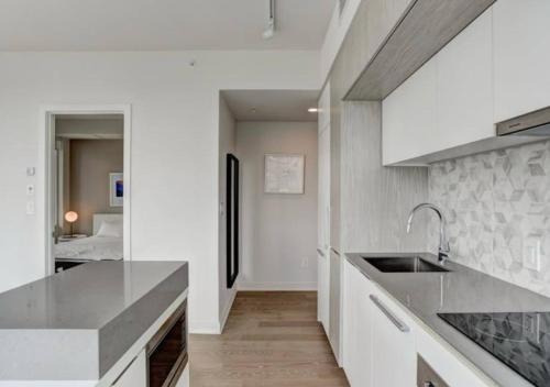 cocina con encimeras blancas, fregadero y cama en TDC2 - 28th floor - 2 bd, 2 bth, en Montreal