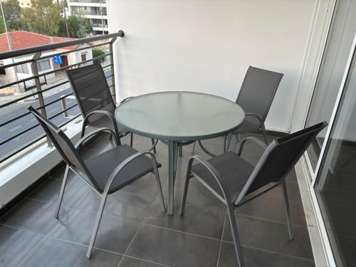 a glass table and chairs on a balcony at Michaela's place in Aglantzia