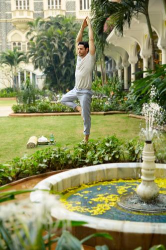 a man doing a yoga pose in front of a fountain at The Taj Mahal Tower, Mumbai in Mumbai