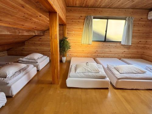 three beds in a room with wooden walls at Tokyo log house with Free parking in Tokyo