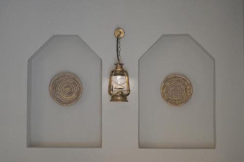 two lights are hanging on a white wall at Nozol Al Rayaheen By Sharjah Collection in Khor Fakkan