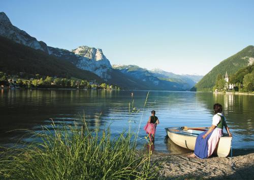 two girls are standing in the water next to a boat at Ferienwohnung Kirchschlager in Bad Aussee