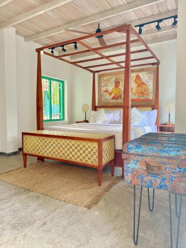 a bedroom with a canopy bed and a table at Tropicana Hideaway Hikkaduwa in Hikkaduwa