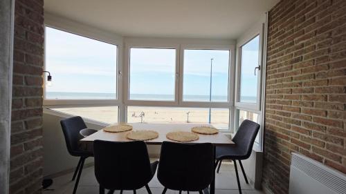 a dining room with a table and a view of the beach at l'Horizon de la digue - Vue mer in Bray-Dunes