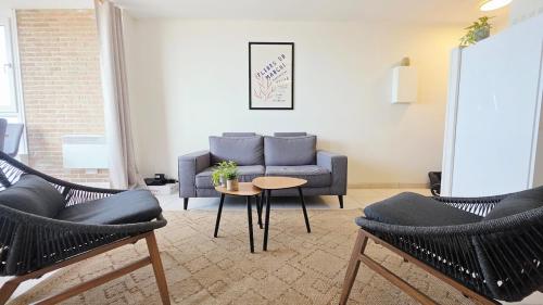 a living room with a couch and a table and chairs at l'Horizon de la digue - Vue mer in Bray-Dunes