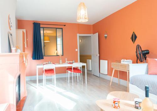 a living room with orange walls and a table and chairs at Sur la route des étoilés - BY PRIMO C0NCIERGERIE in Tournus