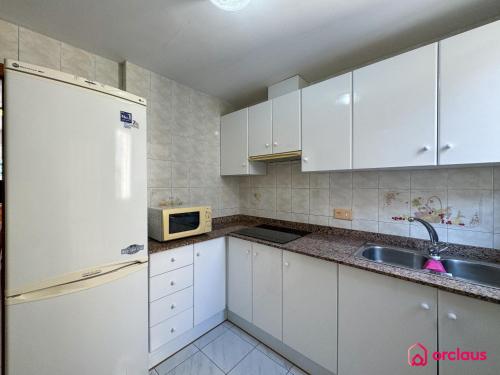 une cuisine avec des armoires blanches, un évier et un réfrigérateur dans l'établissement El Bungalow, à Oropesa del Mar