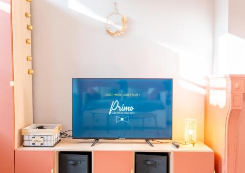 a flat screen tv sitting on top of a cabinet at Sur la route des étoilés - BY PRIMO C0NCIERGERIE in Tournus