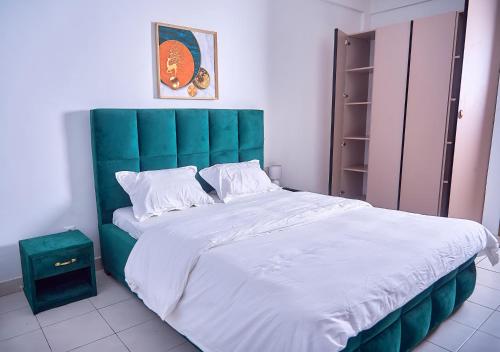 una camera da letto con un letto grande con testiera verde di Appartement A3 a Douala
