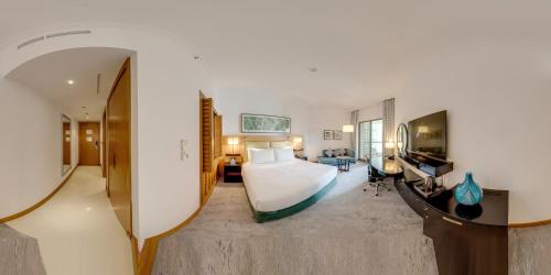 a hotel room with a bed and a living room at Mövenpick Hotel Jumeirah Beach in Dubai