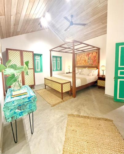 a bedroom with a canopy bed and a table at Tropicana Hideaway Hikkaduwa in Hikkaduwa