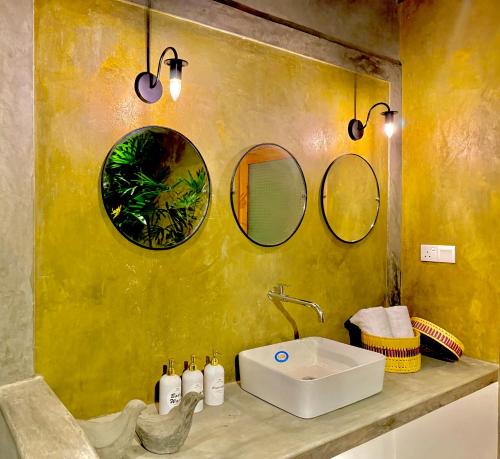 a bathroom with a sink and three mirrors on the wall at Tropicana Hideaway Hikkaduwa in Hikkaduwa