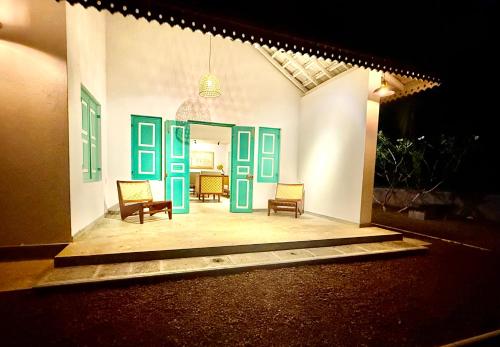 a house with green doors and chairs on a porch at Tropicana Hideaway Hikkaduwa in Hikkaduwa