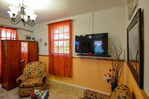 a living room with two chairs and a flat screen tv at River Breeze Villa in Soufrière