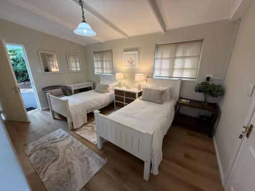a bedroom with two beds and a desk and a table at Railway Cottage at Rawdons Country Estate in Nottingham Road