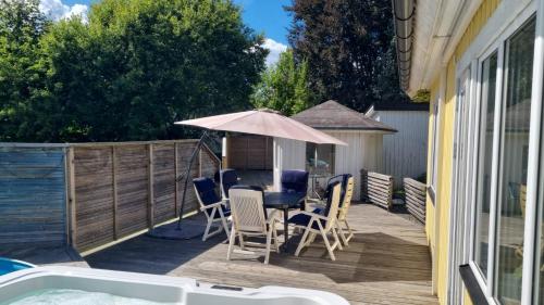 a deck with a table and chairs and an umbrella at Gula huset in Perstorp