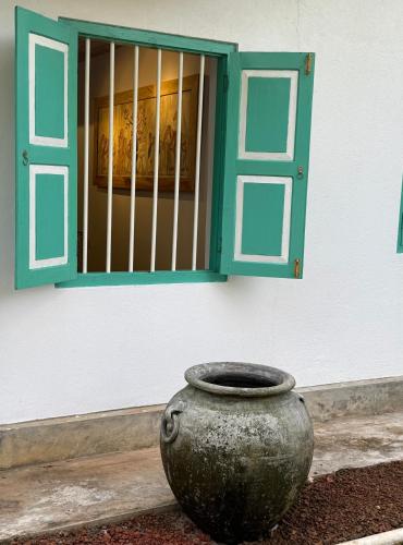 a vase sitting in front of a building with a window at Tropicana Hideaway Hikkaduwa in Hikkaduwa