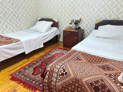 a room with two beds and a rug on the floor at Sweet Baku Hostel in Baku