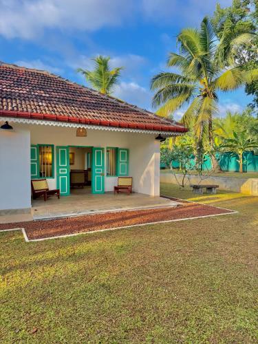 a house with green doors and a palm tree at Tropicana Hideaway Hikkaduwa in Hikkaduwa