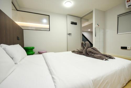 a bedroom with a white bed with a stuffed animal on it at Sunway Grid Loft Suite by Nest Home【Olympic Size Pool】 in Kampong Pendas