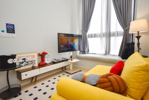 a living room with a yellow couch and a tv at Sunway Grid Loft Suite by Nest Home【Olympic Size Pool】 in Kampong Pendas