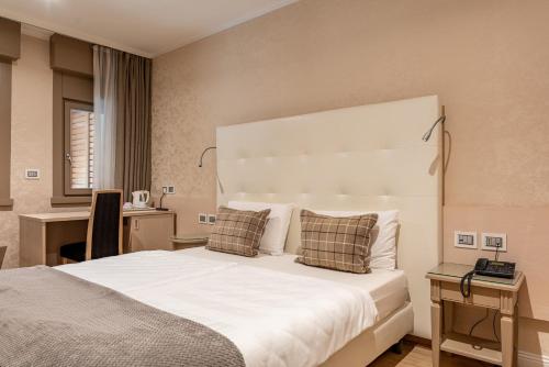 a bedroom with a large white bed and a desk at Hotel Villa Madruzzo in Trento
