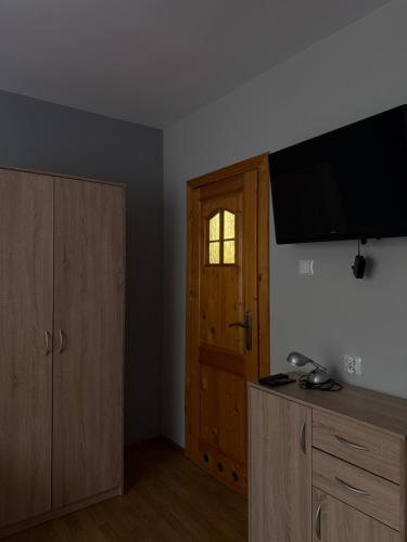 a room with a television and a wooden door at Pokoje Gościnne A i M Dendys in Korbielów