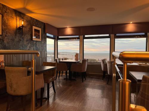 a restaurant with tables and chairs and large windows at The Knowes Hotel & Restaurant in Macduff