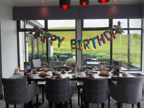 a dining room with a long table with chairs and a sign at The Knowes Hotel & Restaurant in Macduff