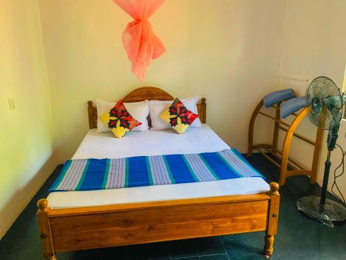 a bedroom with a bed with pillows and a fan at Chill Spot Family Room and Hostel in Sigiriya