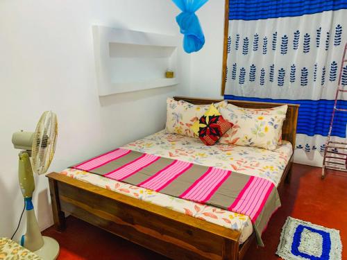a small bedroom with a bed and a fan at Chill Spot Family Room and Hostel in Sigiriya