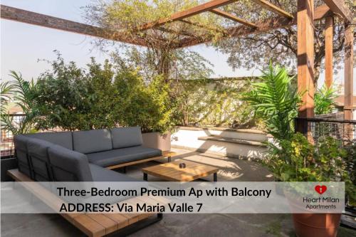 a patio with a blue couch and a wooden table at Heart Milan Apartments San Sepolcro Duomo in Milan