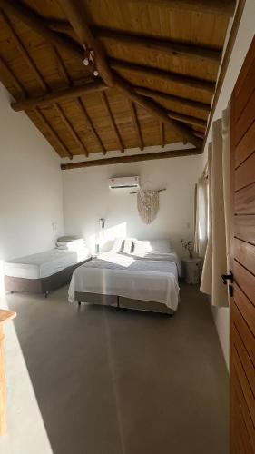 a bedroom with two beds and a wooden ceiling at Casa Odara Trancoso in Trancoso